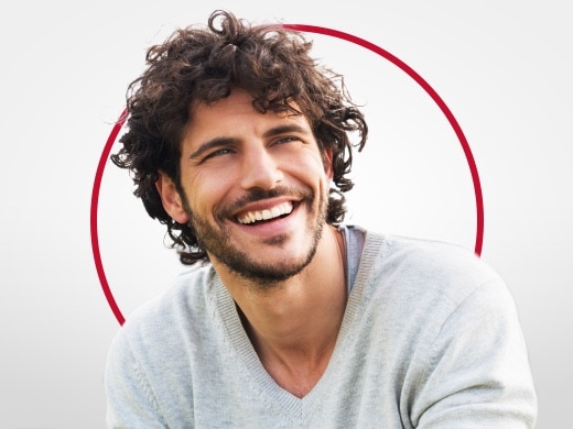 Usměvavý mladý muž v šedém svetru je šťastný po léčbě kvasinkové infekce přípravkem Canesten