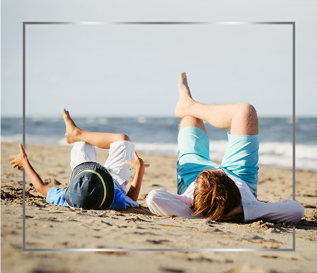 Mother and child lying on beach with crossed legs, happy after Canesten fungal skin infection treatment